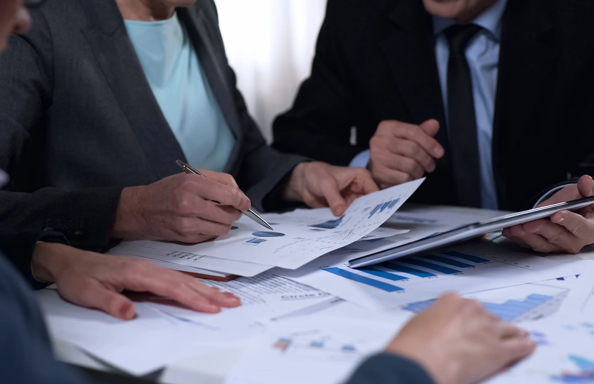 Tre professionisti aziendali analizzano grafici e un tablet per ottimizzare la governance esg e la governance aziendale basata sui dati.