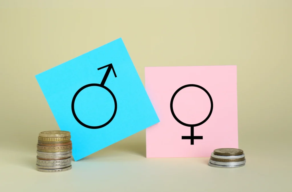 Simboli di genere maschile e femminile su post-it affiancati da due pile di monete di altezza diversa, a rappresentare il gender pay gap